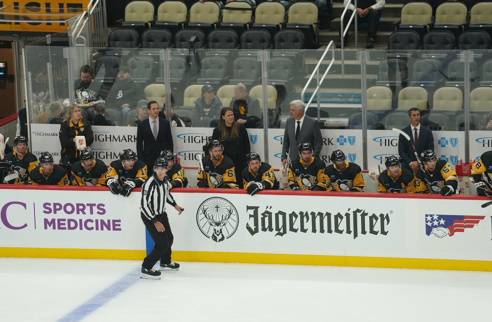 Lauren Rittle, standing at left, behind the bench of the Pittsburgh Penguins.