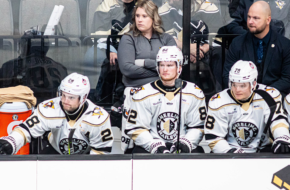 Lauren Rittle stands behind several hockey players in white Wheeling Nailers uniforms.